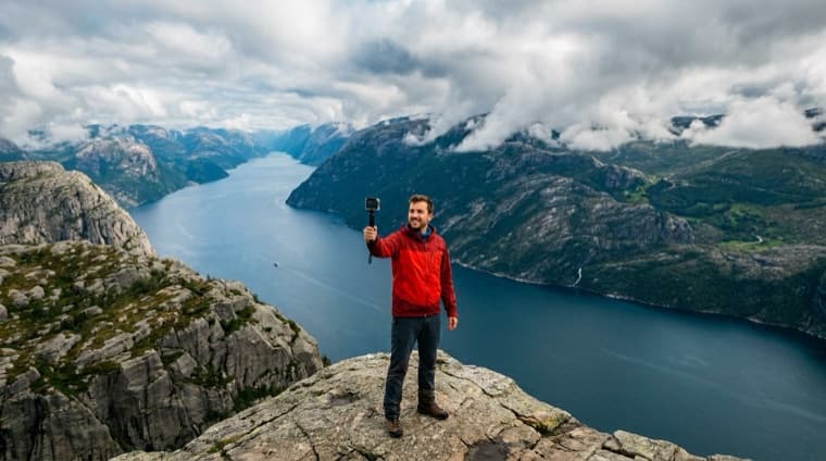 Hiker filming on a ridge above a Norwegian fjord